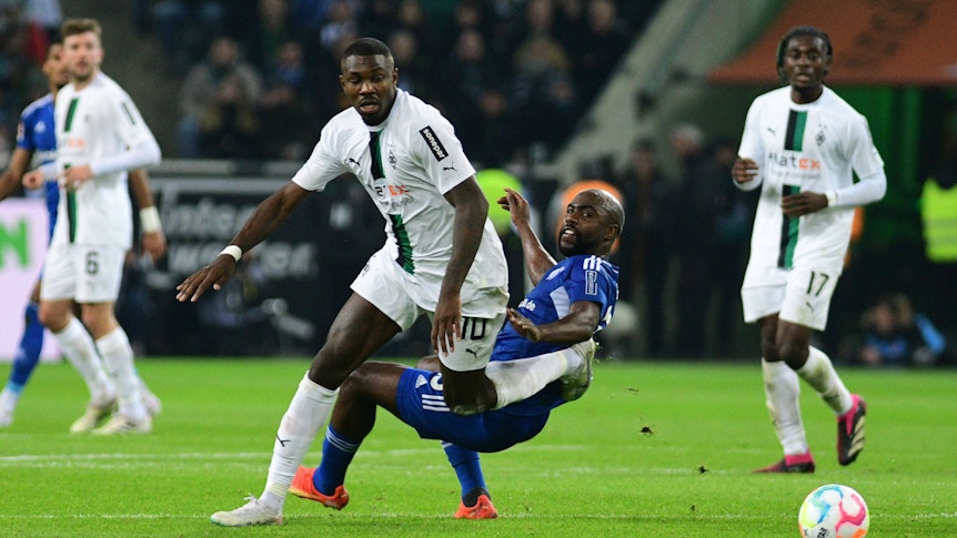 Gladbach-Stürmer Marcus Thuram (M.) im Zweikampf mit Eder Balanta von Schalke 04 während des Bundesliga-Duells am 4. Februar 2023 im Borussia-Park. Im Hintergrund schauen Koné und Kramer zu.