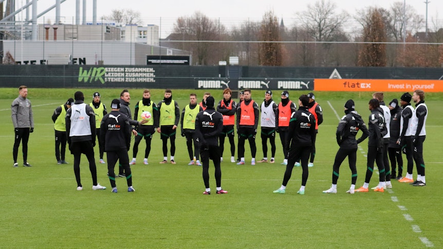 Das Team von Borussia Mönchengladbach steht bei einer Trainingseinheit am 2. Februar 2023 im Borussia-Park im Kreis zusammen. Co-Trainer Edmund Riemer gibt Anweisungen, einige Spieler tragen bunte Leibchen.