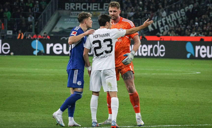 Schalke-Torwart Ralf Fährmann (r.) und Tim Skarke (l.) im Austausch mit Jonas Hofmann (M.) von Borussia Mönchengladbach während des Bundesliga-Duells (4. Februar 2023) im Borussia-Park. Hofmann macht eine Geste, Fährmann blickt ihn derweil an.