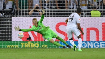 Alassane Plea steht nach einem geschossenen Elfmeter im Spiel von Borussia Mönchengladbach gegen Hertha BSC am 19. August 2022 vor Hertha-Torhüter Oliver Christensen, der dem Ball im rechten Eck hinterherspringt. Plea trägt ein weißes Gladbach-Trikot, Christensen das grüne Torhüter-Trikot von Hertha BSC.