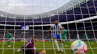 Jessic Ngankam (r.) schiebt den Ball zum zwischenzeitlichen 1:1-Ausgleich im Bundesliga-Spiel von Hertha BSC gegen Borussia Mönchengladbach ein. Jonas Omlin kann den Gegentreffer nicht mehr verhindern. Zu sehen ist, wie der Ball ins Netz des Borussia-Tores fliegt. Omlin springt vergeblich hinterher.