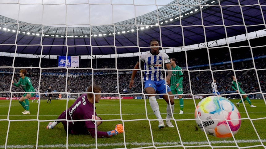 Jessic Ngankam (r.) schiebt den Ball zum zwischenzeitlichen 1:1-Ausgleich im Bundesliga-Spiel von Hertha BSC gegen Borussia Mönchengladbach ein. Jonas Omlin kann den Gegentreffer nicht mehr verhindern. Zu sehen ist, wie der Ball ins Netz des Borussia-Tores fliegt. Omlin springt vergeblich hinterher.