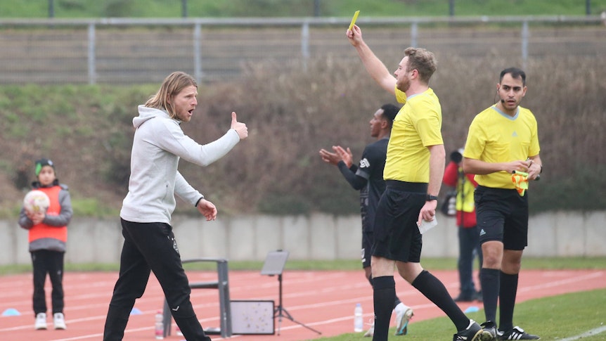 Eugen Polanski (l.) sieht beim Spiel der U23 von Borussia Mönchengladbach gegen Preußen Münster am 12. Februar 2023 die Gelbe Karte vom Schiedsrichter. Aufgenommen wurde das Foto, als Polanski die Verwarnung im Grenzlandstadion gezeigt bekommt. Polanski streckt den Daumen als Reaktion nach oben.