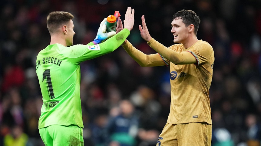 Andreas Christensen (r.) und Marc-André ter Stegen klatschen vor dem Spiel des FC Barcelona bei Atletico Madrid am 8. Januar 2023 mit beiden Händen ein. Christensen trägt das goldene Auswärtstrikot von Barcelona, ter Stegen spielt in einem grünen Trikot.