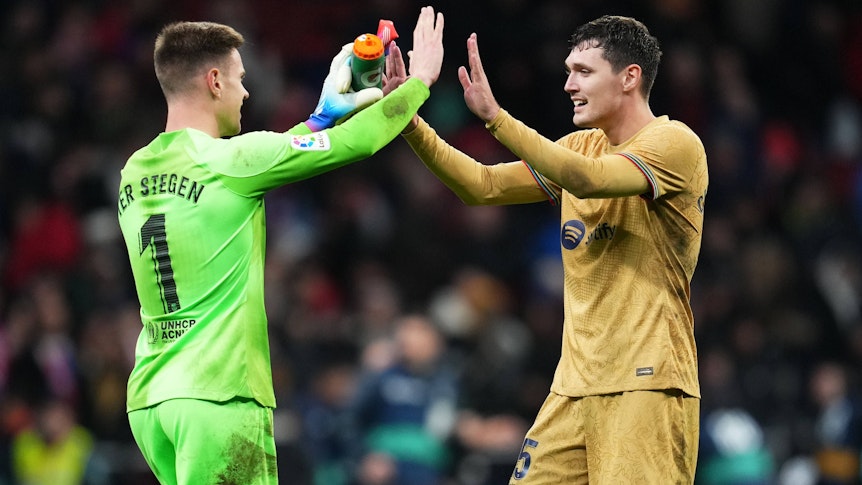 Andreas Christensen (r.) und Marc-André ter Stegen klatschen vor dem Spiel des FC Barcelona bei Atletico Madrid am 8. Januar 2023 mit beiden Händen ein. Christensen trägt das goldene Auswärtstrikot von Barcelona, ter Stegen spielt in einem grünen Trikot.