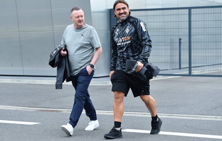 Gladbach-Manager Roland Virkus (l.) und Borussia-Trainer Daniel Farke (r.) im Borussia-Park, hier zu sehen am 26. Juni 2022. Virkus hat eine Jacke im Arm, Farke lächelt.