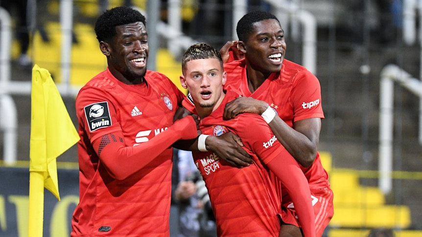 Kwasi Wriedt, Michael Cuisance und Derrick Köhn (v.l.n.r) bejubeln im Trikot von FC Bayern München einen Treffer. Aufgenommen wurd das Foto am 29. November 2019 beim Spiel von Bayern II gegen Carl-Zeiss Jena. Köhn springt Cuisance bei dem Torjubel auf den Rücken.