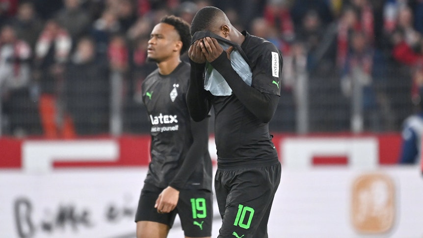Pure Enttäuschung! Gladbach-Stürmer Marcus Thuram (r.) verbirgt sein Gesicht nach der 0:4-Rutsche in Mainz (24. Februar 2023) hinter seinem Trikot. Team-Kollege Nathan Ngoumou (l.) sieht auch nicht glücklich aus.