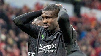 Marcus Thuram steht vor der Auswärtskurve mit den Fans von Borussia Mönchengladbach und fasst sich nach der Bundesliga-Niederlage beim FSV Mainz 05 am 24. Februar 2023 mit beiden Händen an den Kopf.