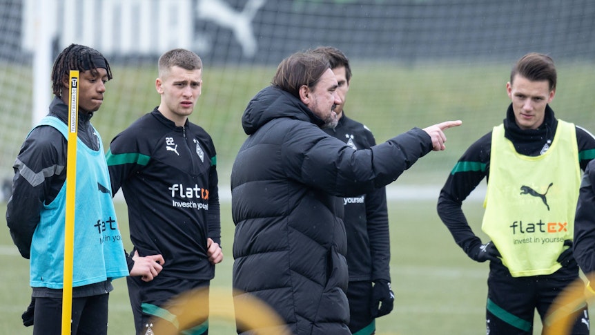Trainer Daniel Farke gibt den Spielern von Borussia im Training Anweisungen, hier am 16. Februar 2023. Yvandro Borges Sanches, Oscar Fraulo, Jonas Hofmann und Hannes Wolf (v. l. n. r.) hören und sehen zu, während Farke mit seinem Finger etwas anzeigt.