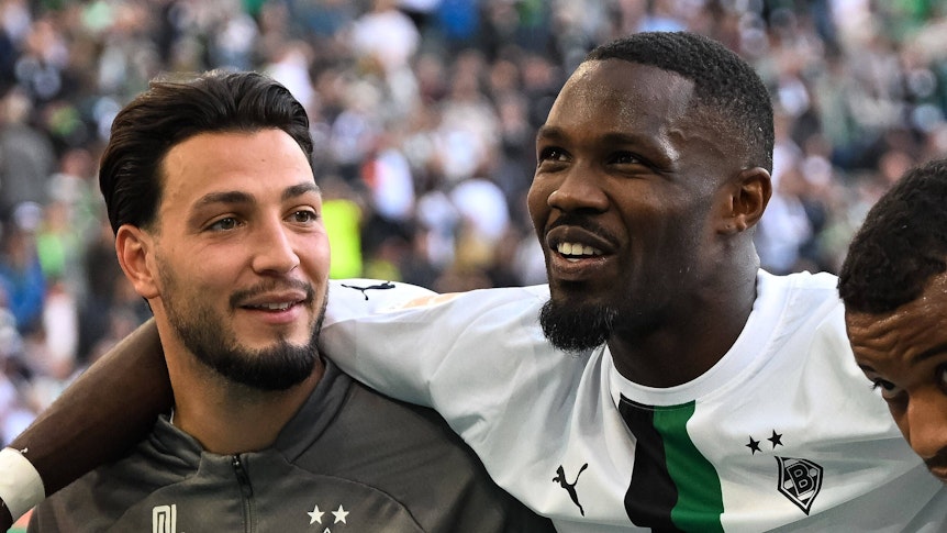 Ramy Bensebaini (l.) und Marcus Thuram (r.) werden Borussia Mönchengladbach aller Voraussicht nach im Sommer ablösefrei verlassen. Das Foto zeigt die beiden am 9. Oktober 2022 gemeinsam mit ihrem Teamkollegen Alassane Plea beim Feiern nach dem gewonnenen Derby gegen Köln mit den Fans.