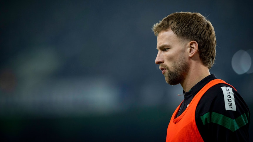 Marvin Friedrich von Borussia Mönchengladbach, hier am 4. Februar 2023 beim Spiel gegen Schalke 04 an der Seitenlinie, kam bisher nur eine Minute für die Fohlen zum Zug. Das Foto zeigt ihn seitlich mit leicht gesenktem Kopf und ernstem Blick im orangen Auswechsel-Leibchen.