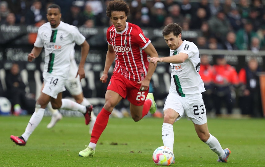 Die Gladbach-Stars Jonas Hofmann (r.) und Alassane Plea (l.) im Laufduell (4. März 2023) mit Kiliann Sildillia vom SC Freiburg im Borussia-Park.