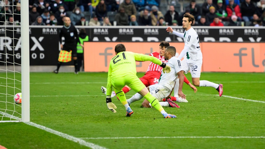 Alassane Plea grätscht den Ball im eigenen Fünfmeterraum beim Bundesliga-Spiel von Borussia Mönchengladbach gegen den SC Freiburg am 4. März 2023 ins Toraus. Hinter ihm lauert Freiburg-Spieler Merlin Röhl, der ebenfalls grätschend auf dem Rasen liegt.. Gladbach-Torhüter Tobias Sippel schaut dem Ball hinterher.
