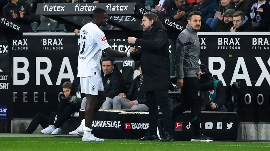 Gladbach-Trainer Daniel Farke (r.) klatscht mit seinem Stürmer Marcus Thuram nach dessen Auswechslung im Bundesliga-Spiel von Borussia Mönchengladbach gegen Werder Bremen am 17. März 2023 ab.
