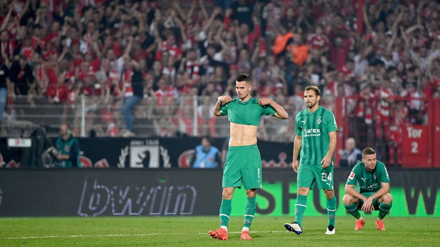 Fans von Union Berlin bejubeln den Sieg ihres Teams im Hintergrund, während Spieler von Borussia Mönchengladbach ihrer Enttäuschung auf dem Rasen im Stadion An der Alten Försterei freien Lauf lassen.