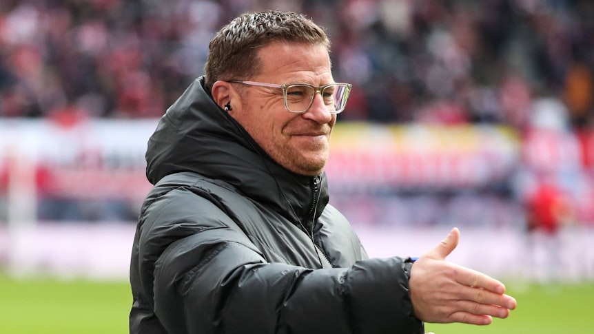 Max Eberl, Geschäftsführer Sport von RB Leipzig, streckt am 11. März 2023 seine rechten Hand zum Handschlag nach vorne und lächelt im Rahmen des Bundesliga-Spiels gegen Borussia Mönchengladbach.