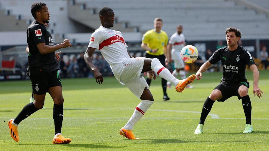 Die Gladbach-Profis Alassane Plea (l.) und Jonas Hofmann (r.) während der Bundesliga-Partie am Samstag (29. April 2023) beim VfB Stuttgart im Duell mit Serhou Yadaly Guirassy (M.). Der Stuttgarter behauptet den Ball.