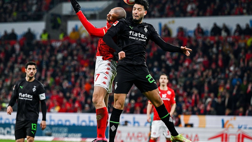 2Mainz-Stürmer Ludovic Ajorque (l.) am 24. Februar 2023 im Luftzweikampf mit Gladbach-Verteidiger Ramy Bensebaini (r.).