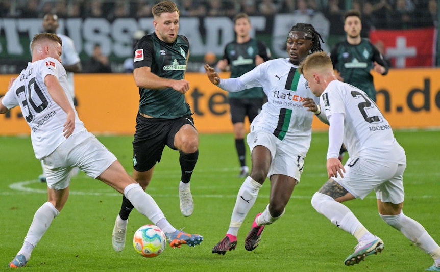 Die Gladbach-Profis Nico Elvedi (l.), Luca Netz (r.) und Manu Koné (2.v.r.) im Duell mit Werder-Bremen-Stürmer Niclas Füllkurg. Das Foto ist am 17. März 2023 im Borussia-Park entstanden. Füllkrug setzt energisch dem Ball nach.