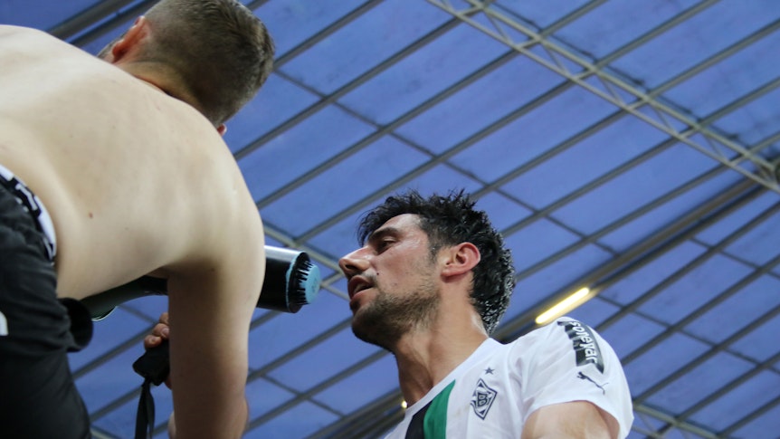 Gladbach-Capitano Lars Stindl ist nach dem 2:2-Remis bei Bayer Leverkusen (21. Mai 2023) von den Borussia-Fans gefeiert worden. Hier steht er auf dem Absperr-Zaun des Gästeblocks und spricht in ein Megafon der Anhänger. Zu sehen sind Stindl und ein Fan.