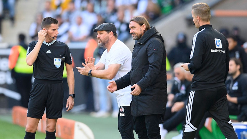 Wer steht am Saisonende vor dem Erzrivalen in der Bundesliga-Abschlusstabelle? Gladbach-Trainer Daniel Farke (2.v.r.) oder Köln-Coach Steffen Baumgart (2.v.l.)? Hier sind die beiden am 9. Oktober 2022 im Borussia-Park zu sehen. Beide Trainer machen Gesten mit ihren Händen.