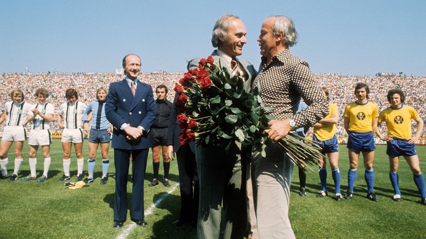 Amtsübergabe auf dem Rasen. Am 33. Spieltag der Bundesliga-Saison 1974/75 wird Trainer Hennes Weisweiler (r.) von Borussia Mönchengladbach verabschiedet und sein Nachfolger, Udo Lattek, begrüßt. Im Hintergrund Gladbach-Manager Helmut Grashoff. Das Foto stammt vom Spiel Borussia Mönchengladbach gegen Eintracht Braunschweig am 7. Juni 1975.