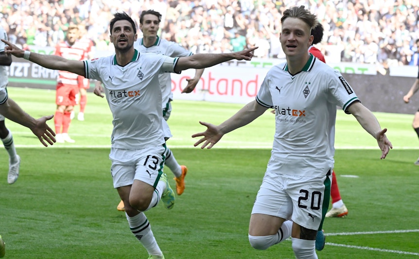 Luca Netz (r.) und Lars Stindl jubeln über einen Treffer von Borussia Mönchengladbach im Bundesliga-Finish (27. Mai 2023) gegen den FC Augsburg im Borussia-Park. Sie breiten die Arme zum Jubel aus.