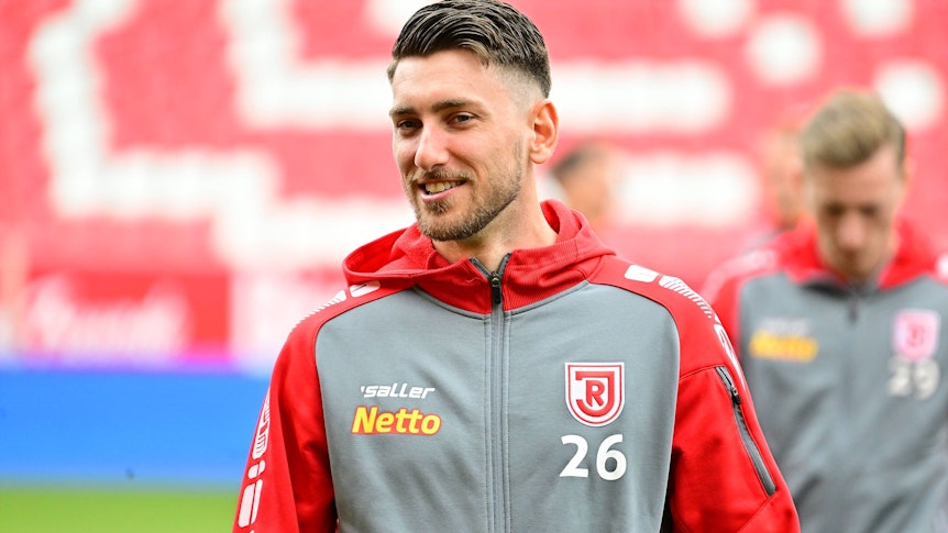 Charalambos Makridis, Ex-Spieler aus der U23 von Borussia Mönchengladbach, am 23.04.2023 vor einem Zweitligaspiel des SSV Jahn Regensburg gegen den 1. FC Kaiserslautern lächelnd.