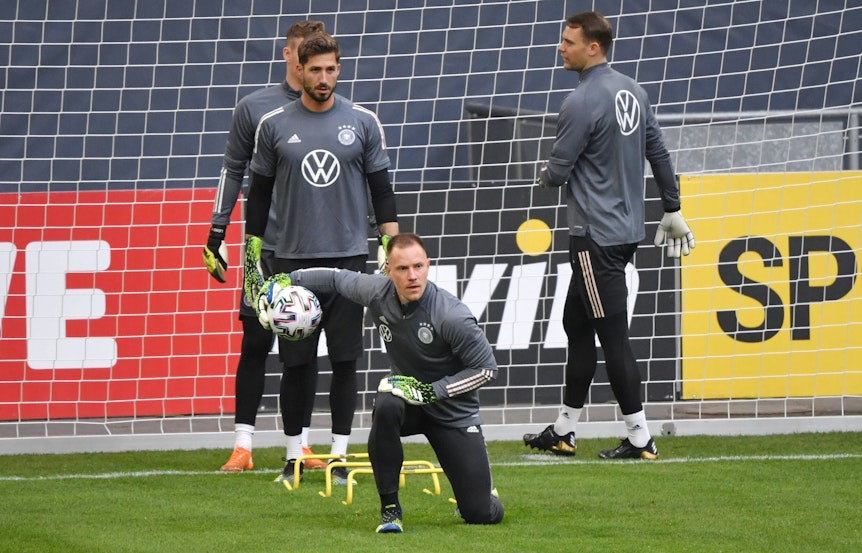 DFB-Torwart und Ex-Gladbach-Profi Marc-André ter Stegen (M.), hinter ihm sind auch Kevin Trapp und Manuel Neuer (r.) zu sehen. Das Foto ist am 23. März 2021 entstanden. Ter Stegen kniet und hat den Ball in einer Hand.