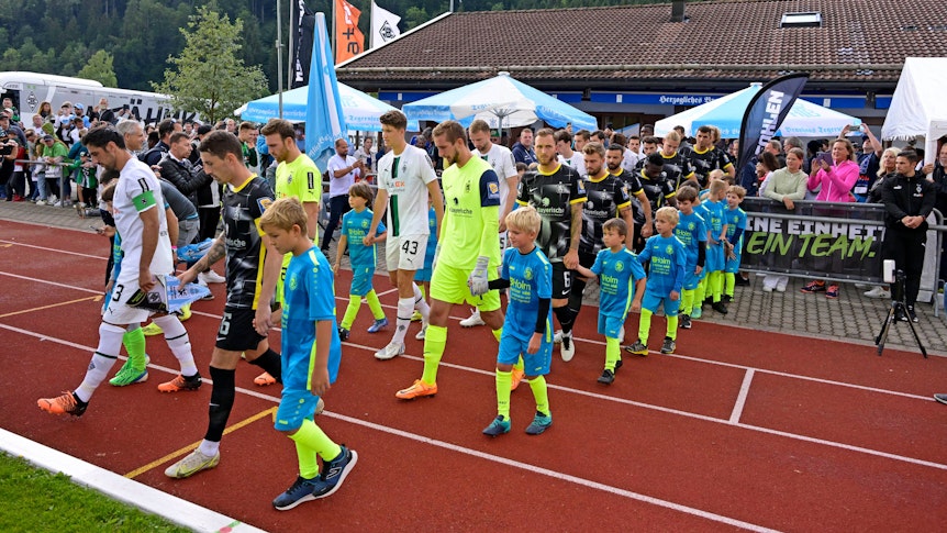 Auch in dieser Sommervorbereitung trägt Borussia Mönchengladbach wieder ein Testspiel auf dem Sportplatz Birkenmoos in Rottach-Egern aus. Das Foto stammt vom letztjährigen Test gegen 1860 München am 10. Juli 2022. Die Teams laufen vor dem Spiel auf das Feld.