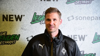 Oliver Kirch, hier am 17. Dezember 2022 im Borussia-Park zu sehen, ist der neue U19-Trainer bei Fußball-Bundesligist Borussia Mönchengladbach. Kirch steht vor einer Fotowand, auf der Legenden des Parks zu lesen ist.