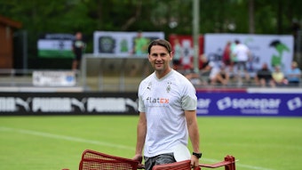 Gerardo Seoane hält am 23. Juli 2023 bei einer Einheit im Trainingslager in Rottach-Egern mehrere Spiel-Figuren in den Händen und steht auf dem Rasen am Sportplatz Birkenmoos.