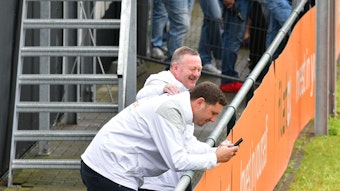 Roland Virkus klopft Nils Schmadtke (schaut auf sein Handy) am 2. August 2023 beim Training von Borussia Mönchengladbach auf den Rücken.