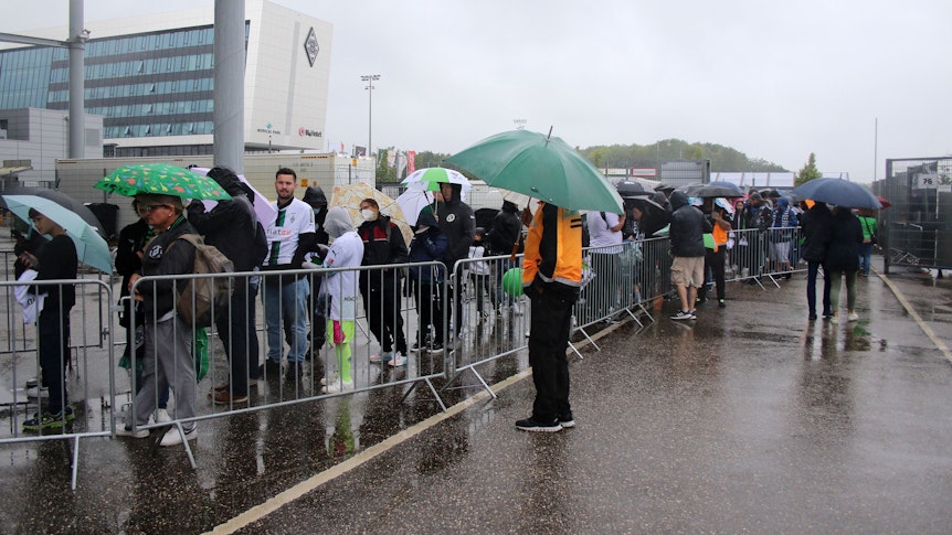 Wir sind Borussi-JA! Tausende Gladbach-Fans stehen trotz Dauerregens am Sonntag (6. August 2023) beim Familienfest samt Saisoneröffnung im Borussia-Park an, um Autogramme von den Fohlen-Stars erhaschen zu können. Zu sehen ist eine Menschenschlange und zahlreiche Regenschirme.