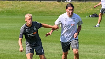 Gladbach-Profi Oscar Fraulo (l.), hier zu sehen am 11. Juli 2023 an der Seite von Cheftrainer Gerardo Seoane (l.) auf dem Trainingsgelände im Borussia-Park. Beide haben das Geschehen vor ihnen im Blick.