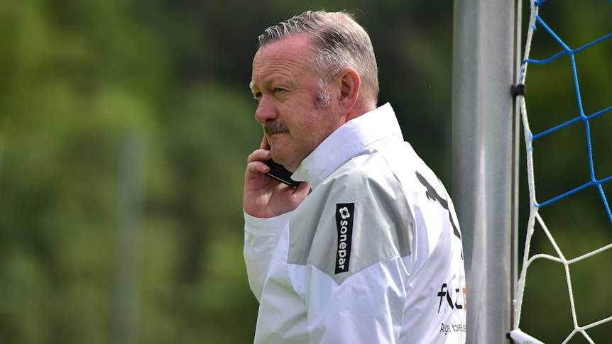 Roland Virkus hält im Trainingslager von Borussia Mönchengladbach am 27. Juli 2023 ein Handy am Ohr.