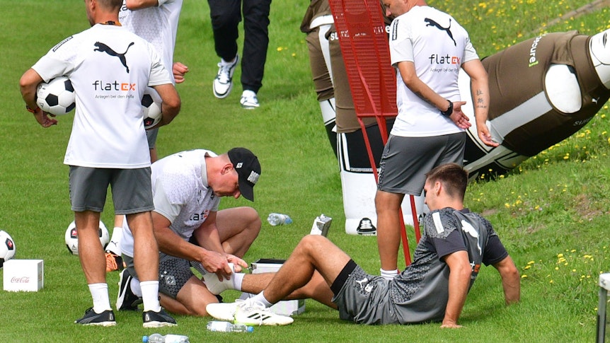 Maximilian Wöber (liegend) ist im Training von Borussia Mönchengladbach am 24. August 2023 umgeknickt und muss behandelt werden.