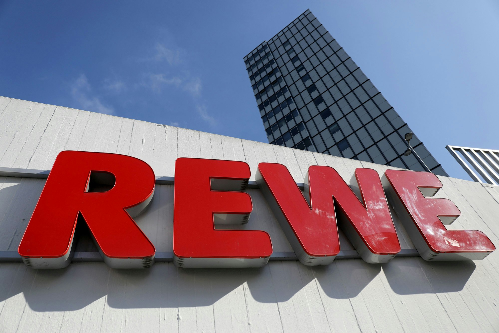 Ein Rewe-Schriftzug hängt vor einem Supermarkt, hier im April 2021 in Köln.