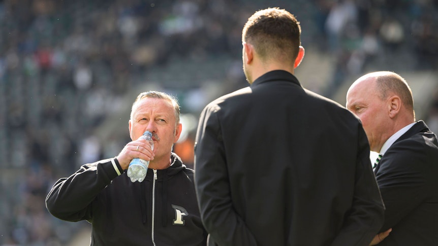 Roland Virkus, Nils Schmadtke und Stephan Schippers unterhalten sich am Spielfeldrand im Borussia-Park.