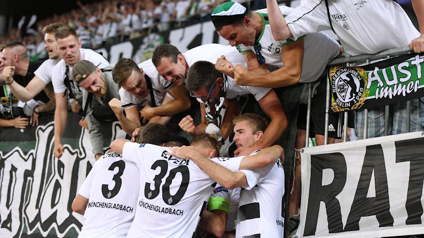 Spieler von Borussia Mönchengladbach feiern mit Gladbach-Fans in der Nordkurve.