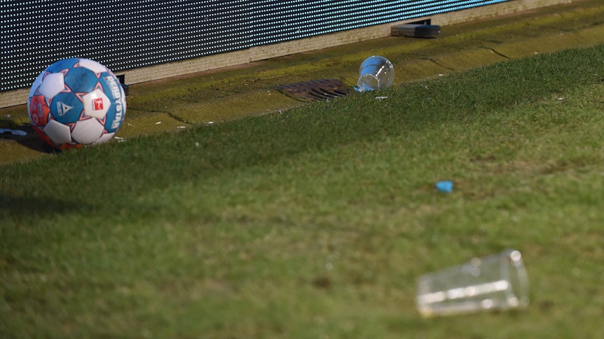 Zwei Bierbecher liegen im Bochumer Ruhrstadion neben einem Ball.