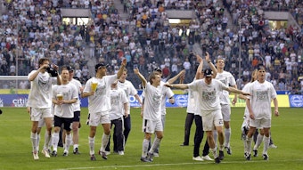 Gladbach Spieler feiern und tanzen zusammen auf dem Platz. Im Hintergrund sind die Fans.