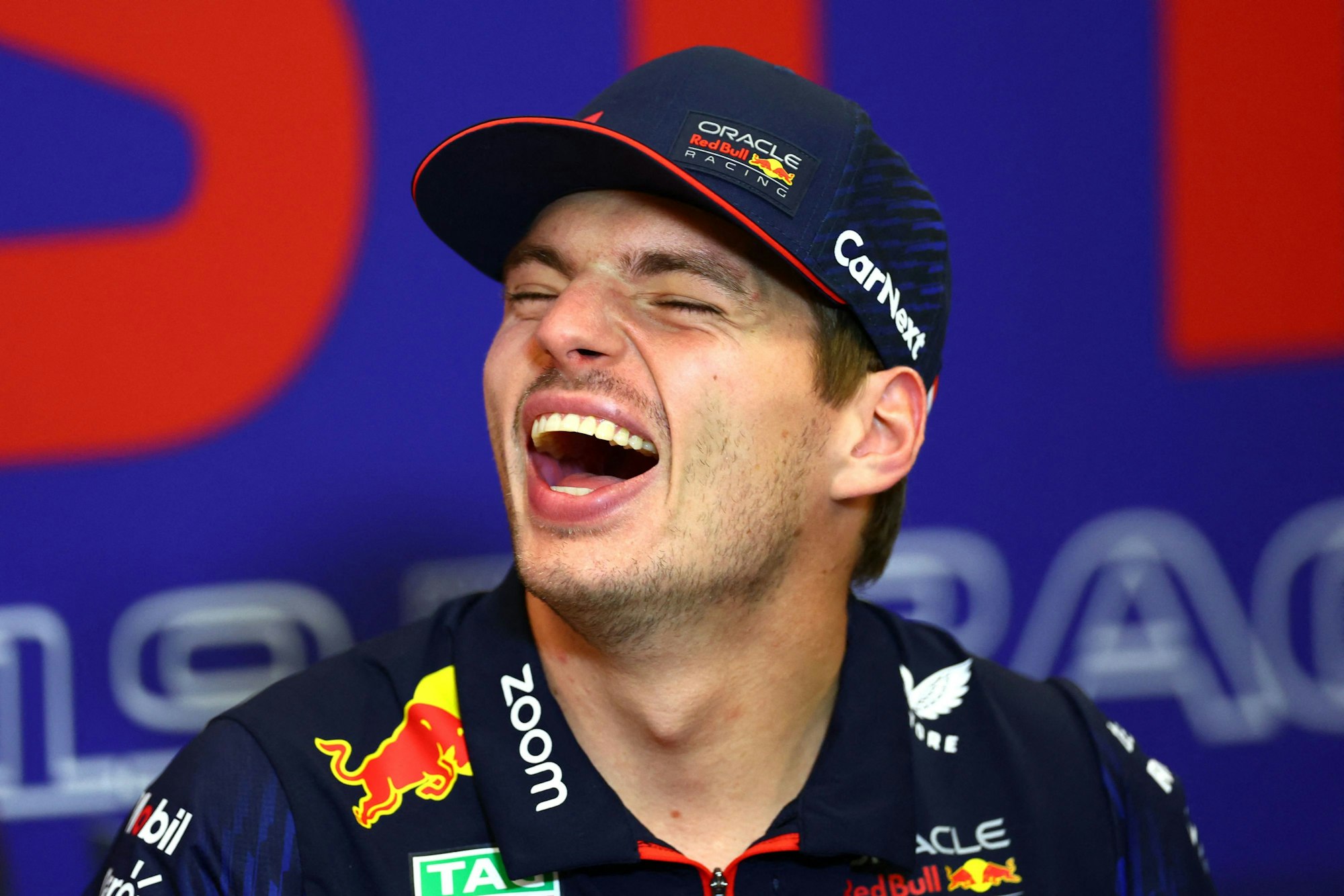 Max Verstappen lacht bei einer Pressekonferenz.