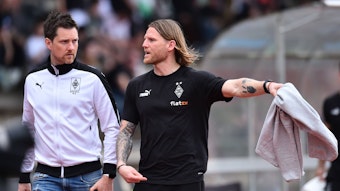 Nachwuchs-Chef und U23-Coach von Borussia Mönchengladbach. Letztgenannter streckt seinen linken Arm aus.
