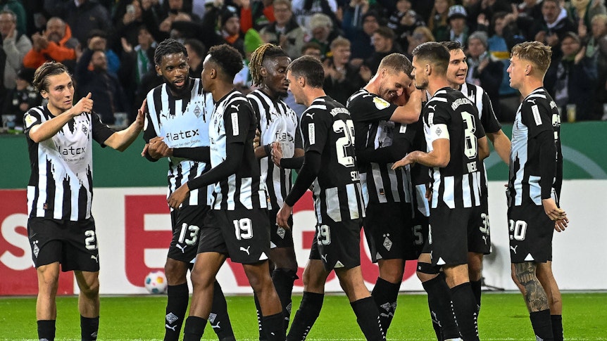 Mehrere Gladbachspieler jubeln gemeinsam im schwarz-weißen Trikot.