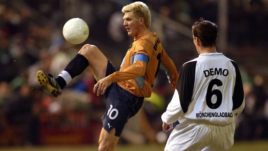 Stefan Effenberg im orangen Wolfsburg-Trikot spielt den Ball. Igor Demo versucht im Trikot von Borussia Mönchengladbach dazwischenzugehen.