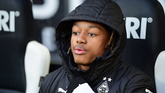 Yvandro Borges Sanches sitzt in einer Borussia-Jacke auf der Auswechselbank.