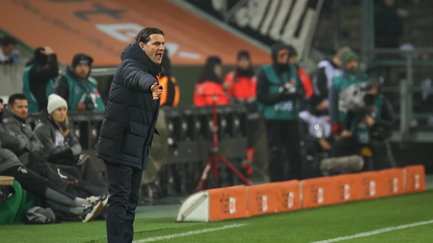 Trainer von Borussia Mönchengladbach dirigiert während eines Heimspiels an der Seitenlinie.