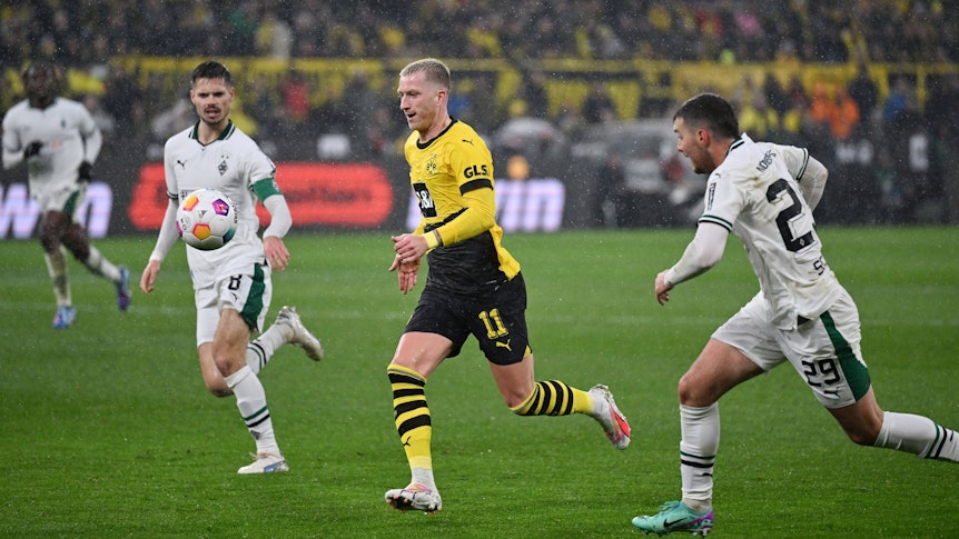 Julian Weigl, Marco Reus und Joe Scally schauen auf den Ball.